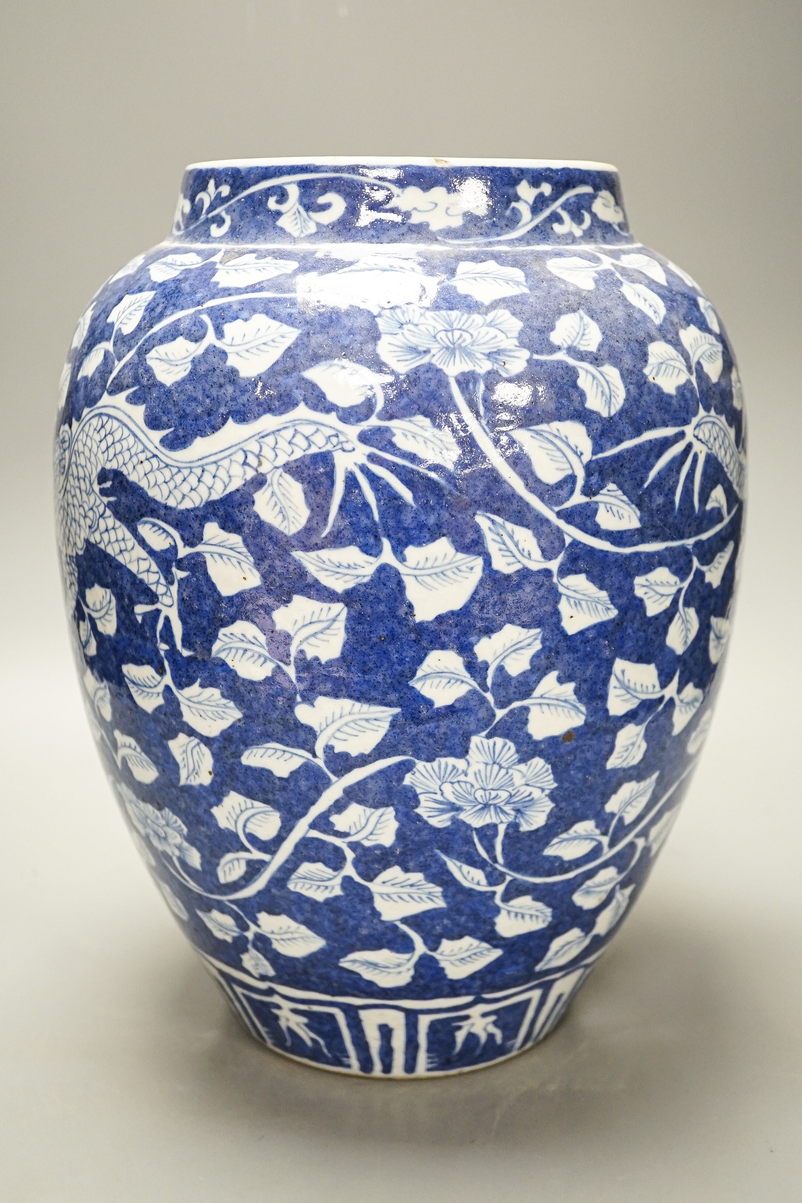 A Chinese blue and white ovoid jar, 19th/20th century, painted with dragons amid flowers and foliage, 33 cms high.